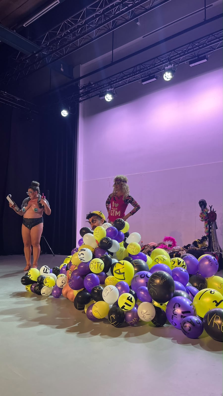 Performers on stage in a show with a pile of balloons with words written on them
