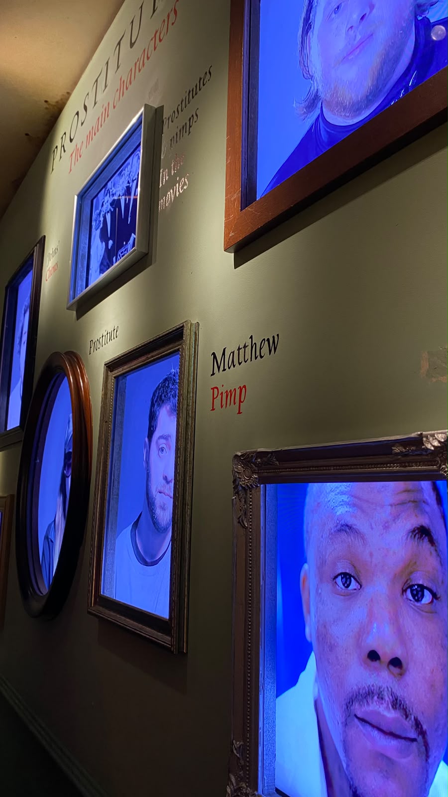 Museum wall with video portraits titled Prostitutes: the main characters